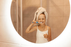 A girl brushes her teeth, illustrating proper Toothbrushing Techniques by Age in Beverly Hills.